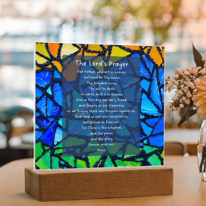 Stylized 'The Lord's Prayer' card with colorful abstract design on a wooden stand.